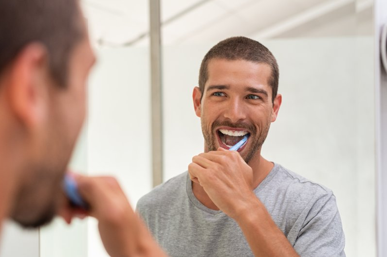 A Man Brushing Teeth Looking at the Mirror